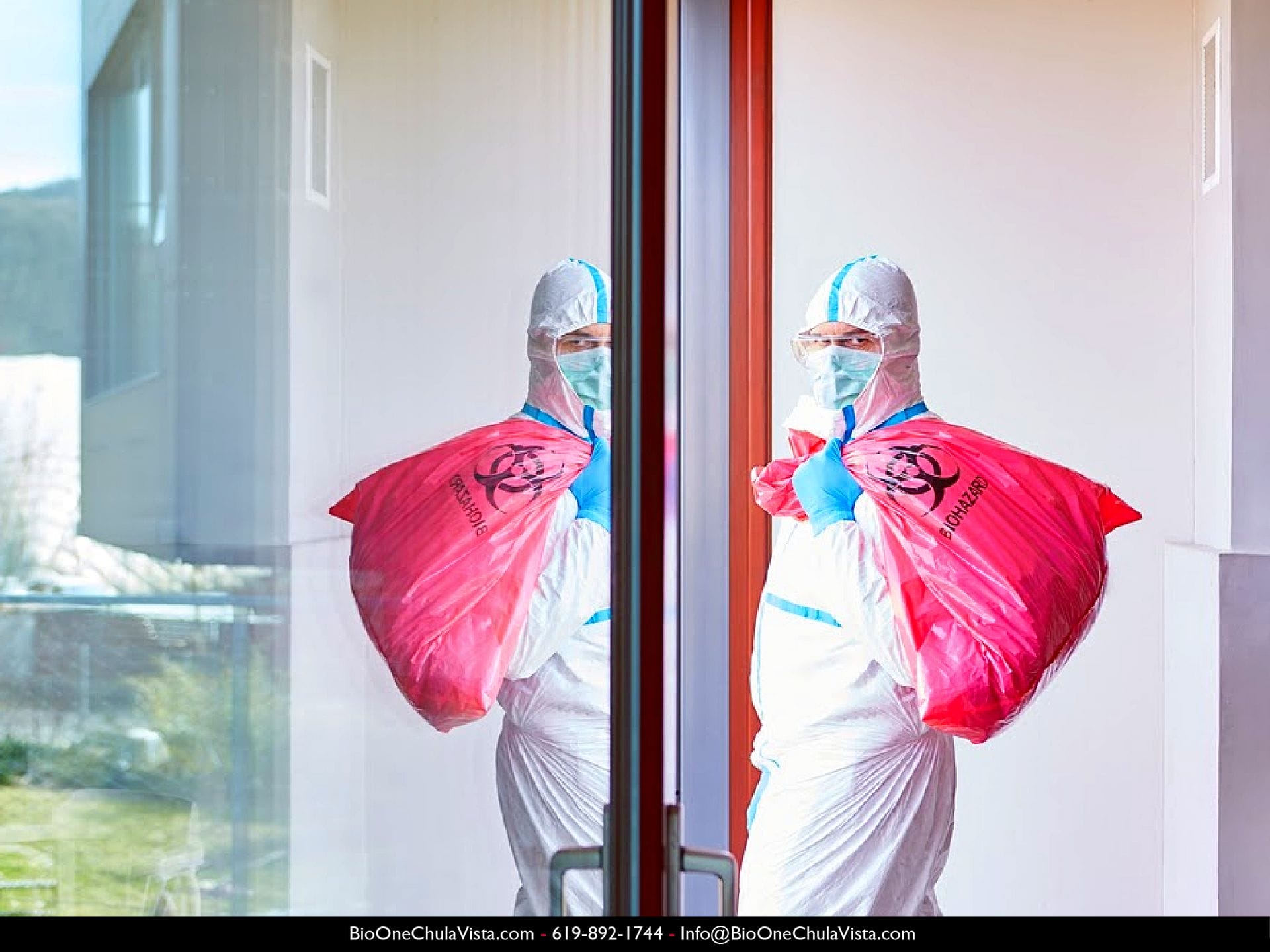 Image shows technician dressed with hazmat and PPE, as he takes out a red bag of biohazardous waste.